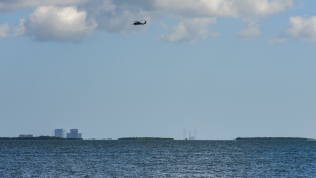Military helicopters patrol the launch area prior to launch